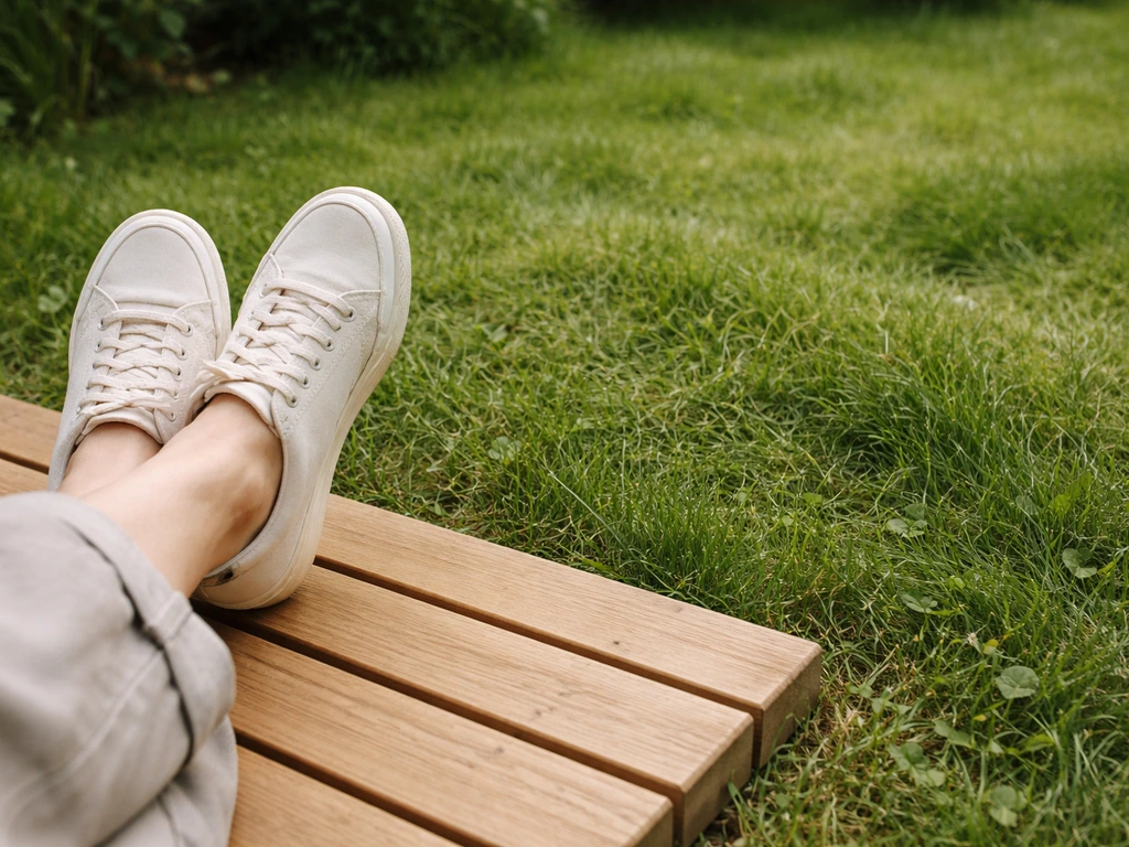 Pieds posés sur un caillebotis en bois au-dessus d’un gazon, ambiance jardin minimaliste.